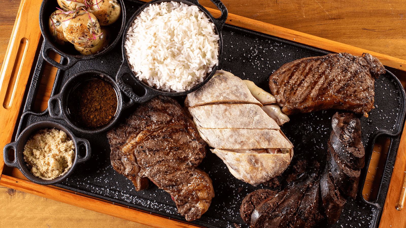 Corte argentino em Campinas: dois bifes grelhados na brasa, arroz, batatas e farofa na tábua de ferro do Ramalho Experience