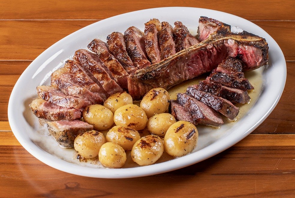 Bife de dry aged de alta qualidade, servido em uma tábua de madeira com sal grosso, no restaurante Ramalho Experience em Campinas